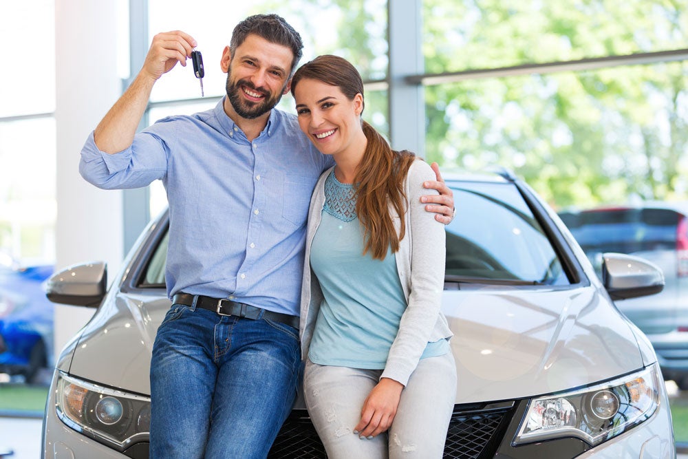 A smiling man and woman holding up a set of car keys